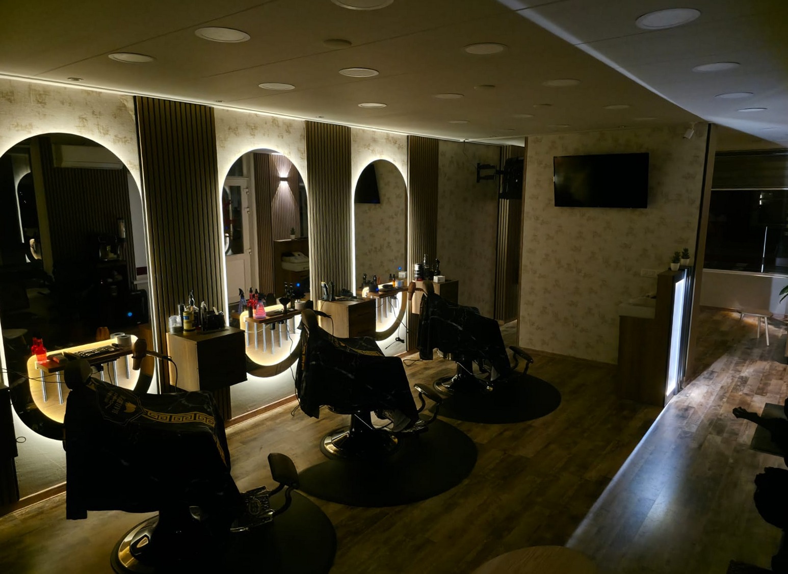 Drie stoelen voor drie verlichte spiegels in Kapsalon Oscar